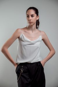 JAGYCH AW 25 ESSENTIALS BRUTAL REFINEMENT STRAP BLOUSE IN WHITE CRYSTAL CROSS EARINGS TROUSERS CHAIN